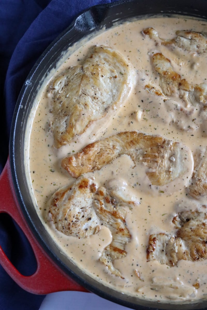 chicken breast in creamy sauce in a skillet simmering 