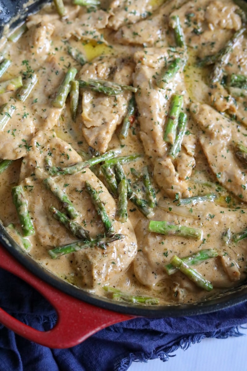 chicken and asparagus in cream sauce in a skillet 