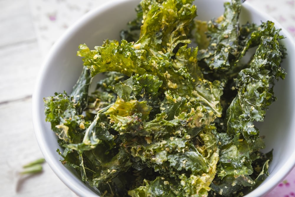 Close up color photo with delicious kale chips on white bowl, ready to enjoy a gourmet snack.