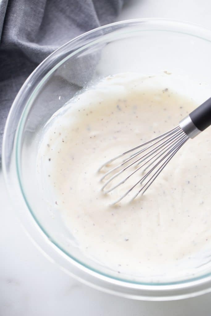 mayo salad dressing in a clear bowl with a whisk