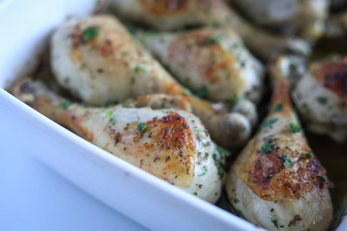 roasted drumsticks in a white baking dish with seasoning
