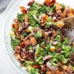 broccoli, bacon, cheese, onion and dressing in a clear bowl