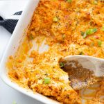 keto buffalo chicken casserole in white baking dish with a wooden spoon