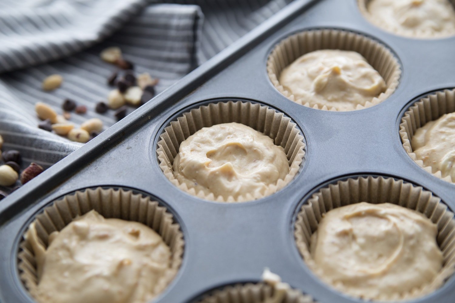 raw cheesecake batter in a muffin tin lined with cupcake liners