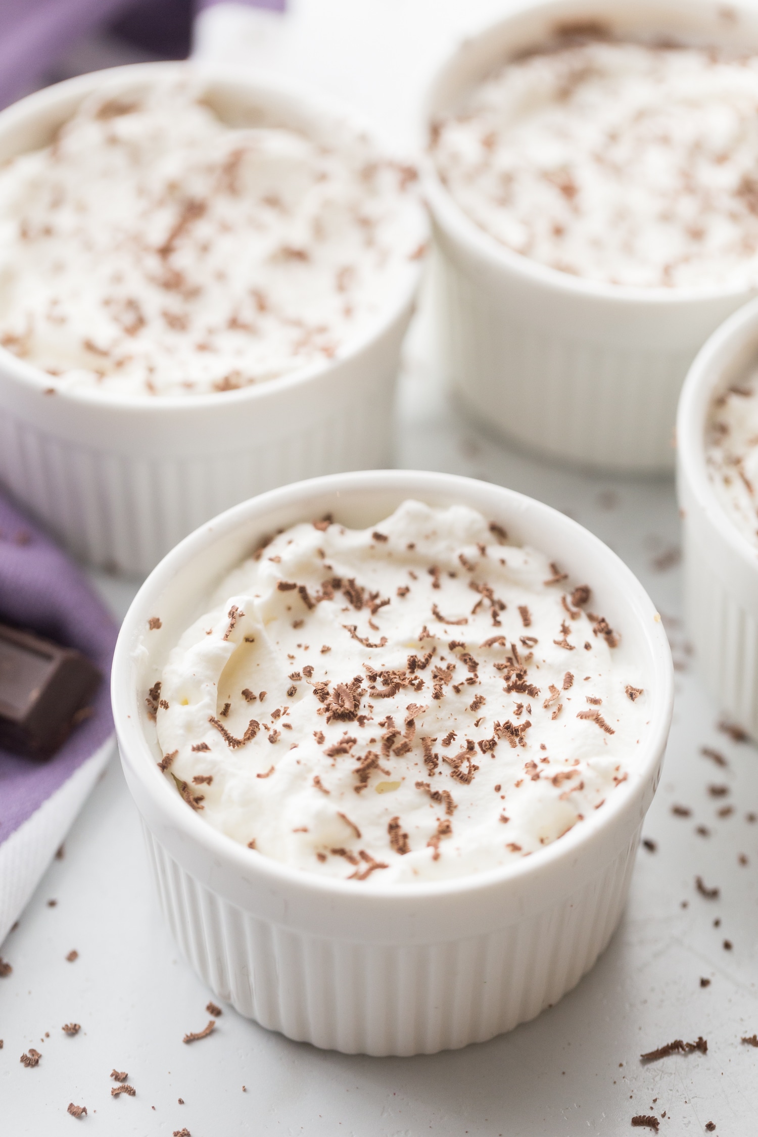 Mousse in ramekins with homemade whipped cream and chocolate shaving sprinkled over the top.
