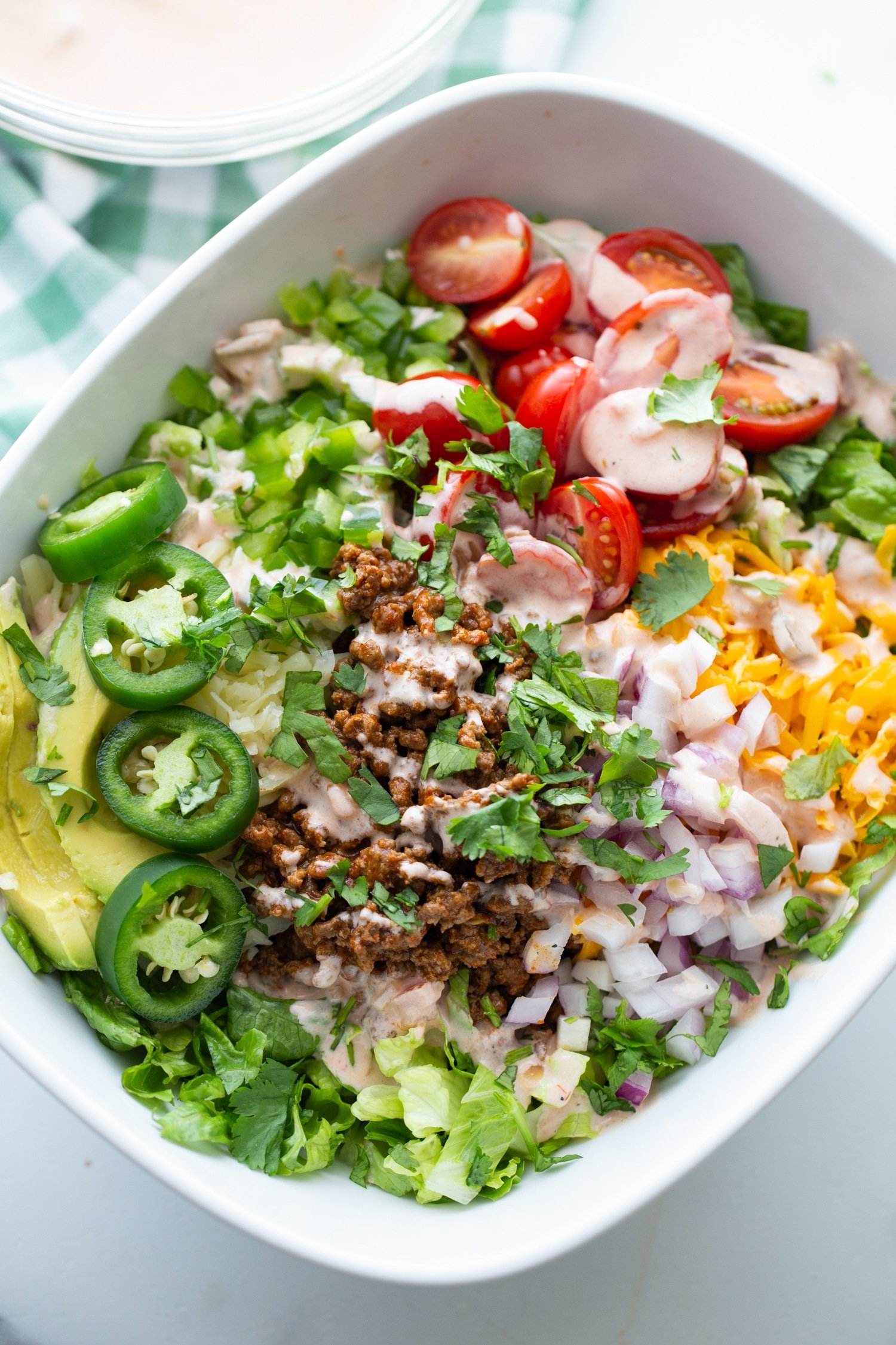 taco salad without tortilla shell in a white bowl with dressing