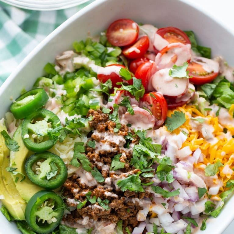healthy keto taco salad recipe in a bowl with tomatoes, lettuce, ground beef, and cheese