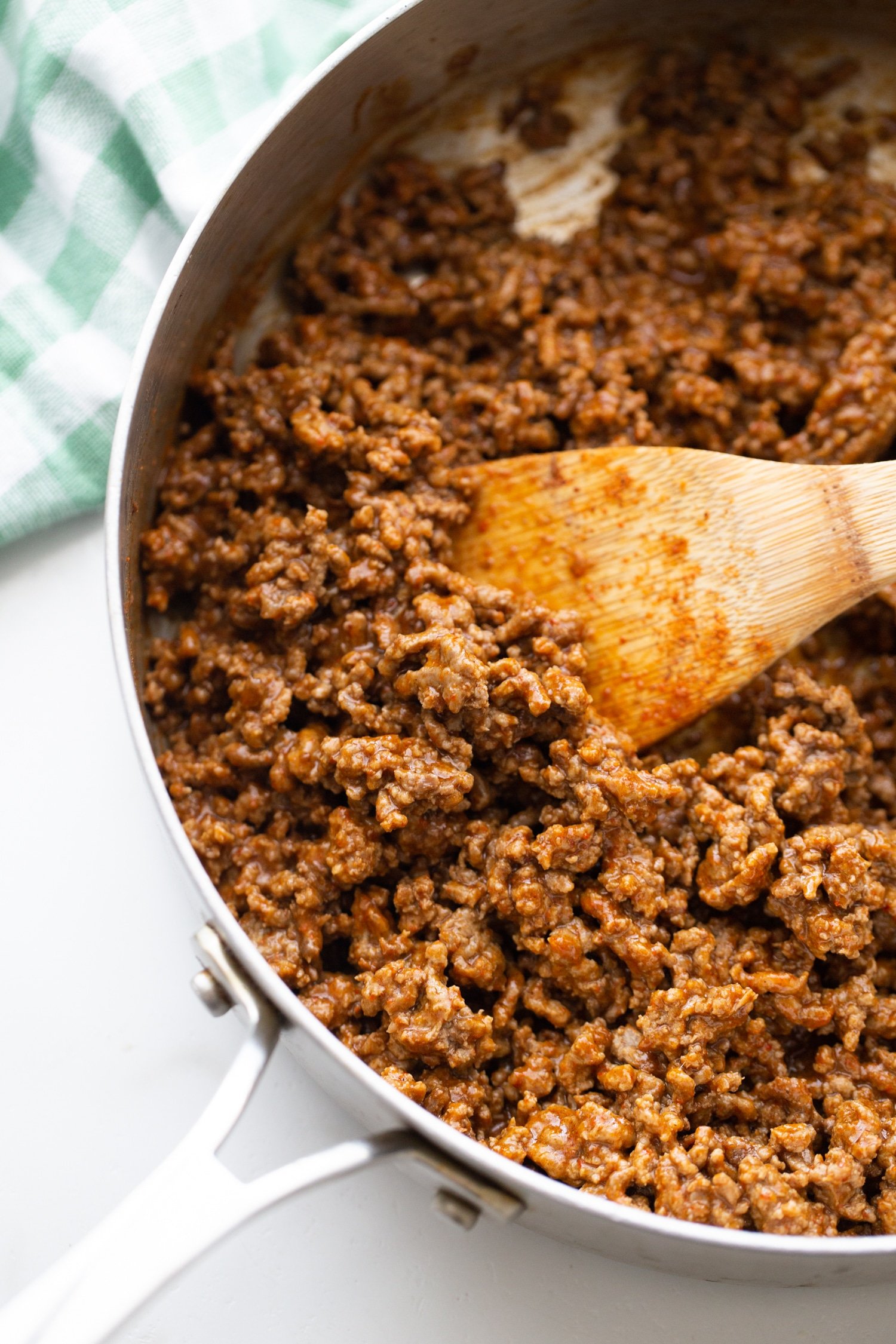 ground beef with taco seasoning sauteeing in skillet with wooden spoon