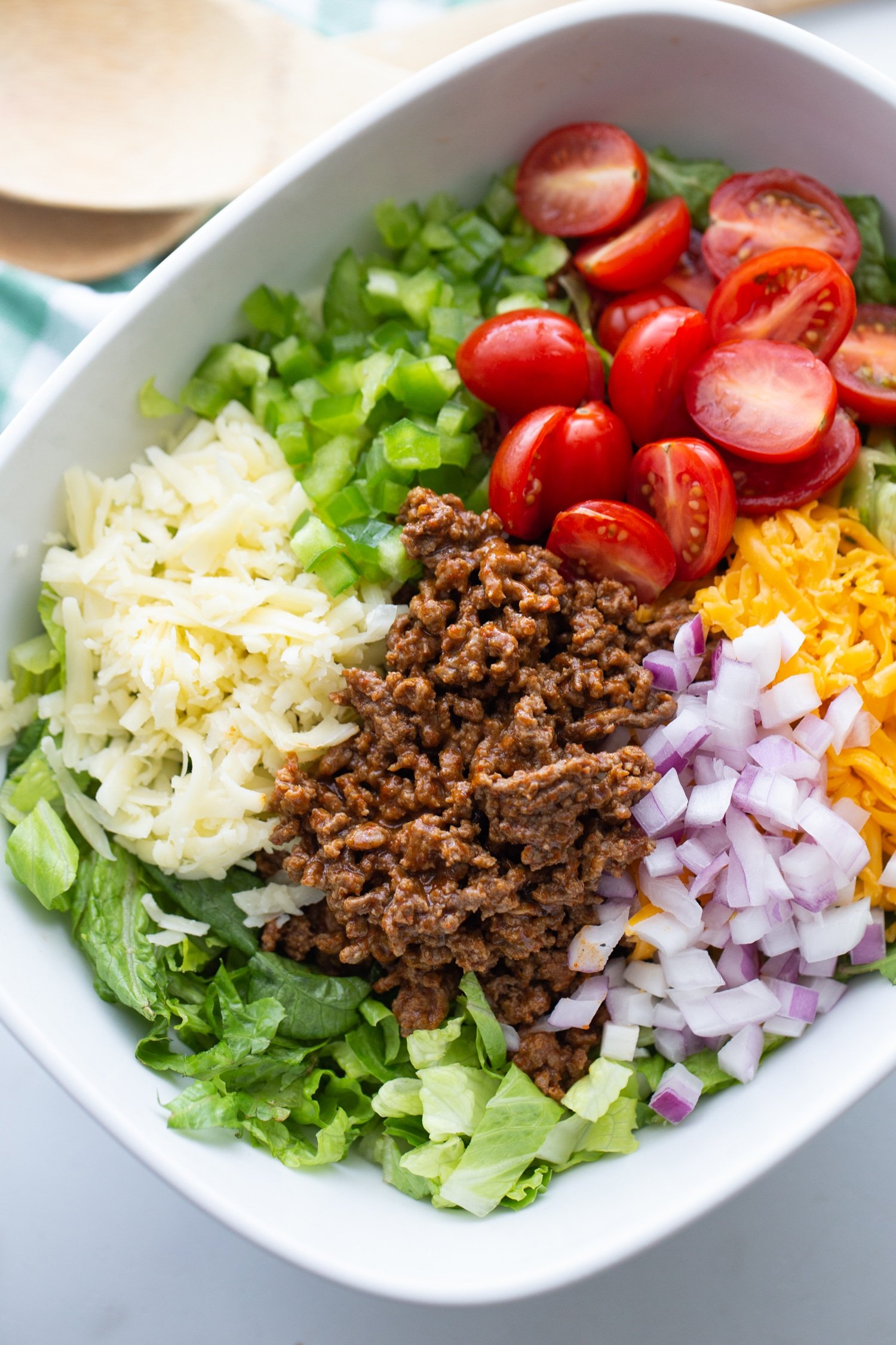 keto salad in a white bowl with ground beef, tomatoes, cheese, peppers, and onions