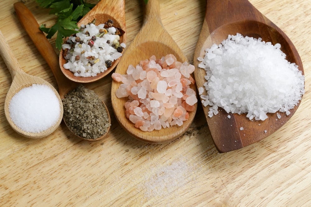 different types of salts in wooden spoons displayed on a table