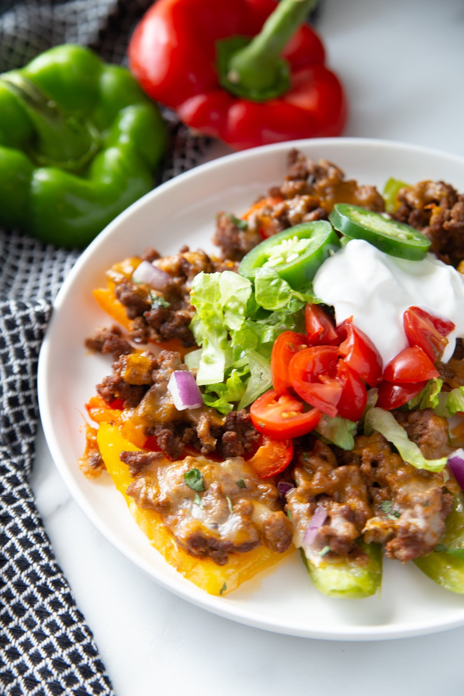 low carb nachos on a white plate with ground beef, cheese and veggies