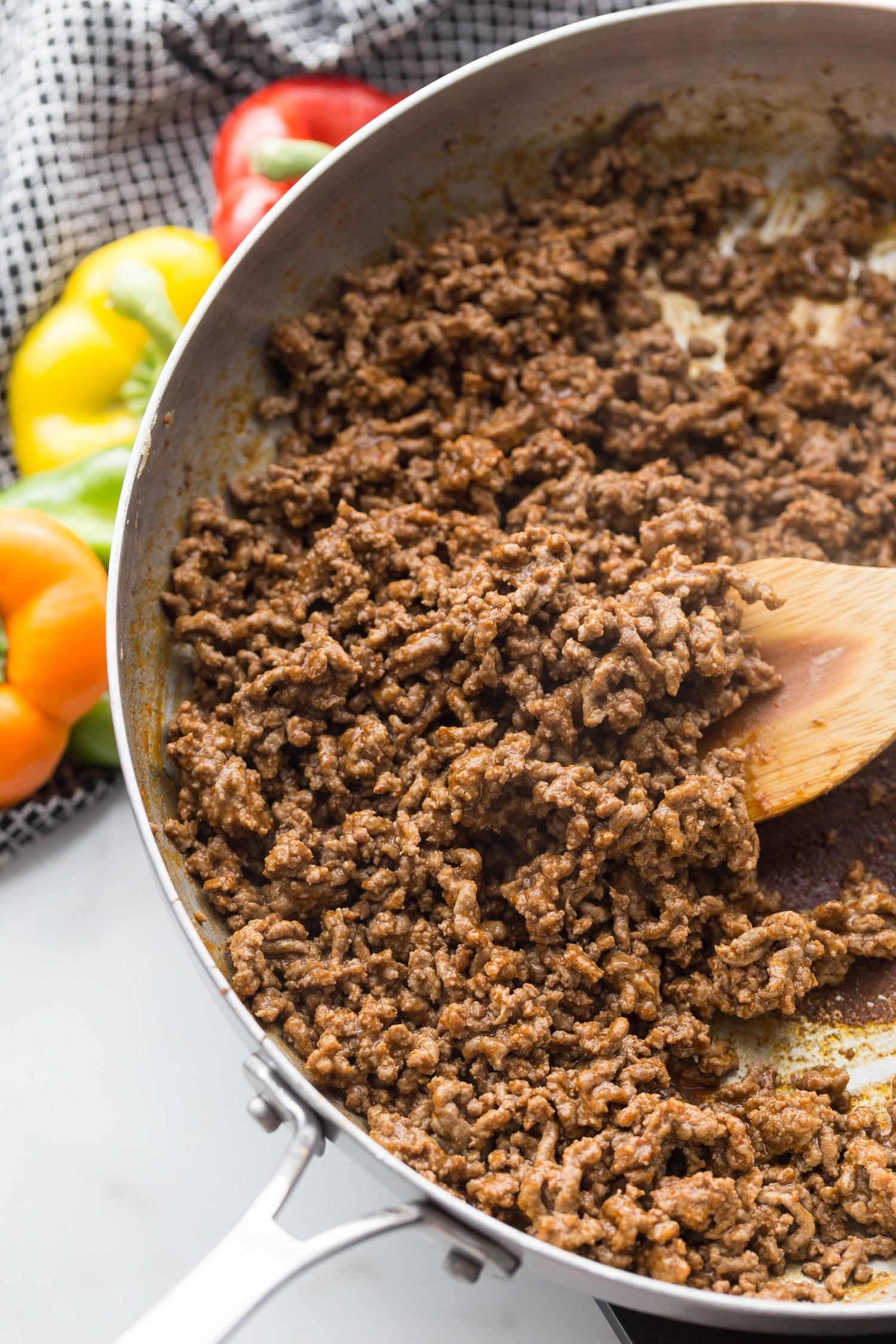ground meat in a skillet with taco seasoning and wooden spoon