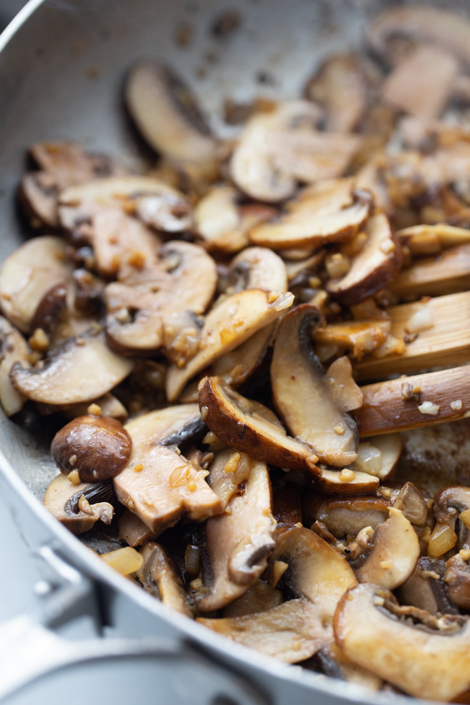 cremini mushrooms sauteeing in a skillet with onions and garlic