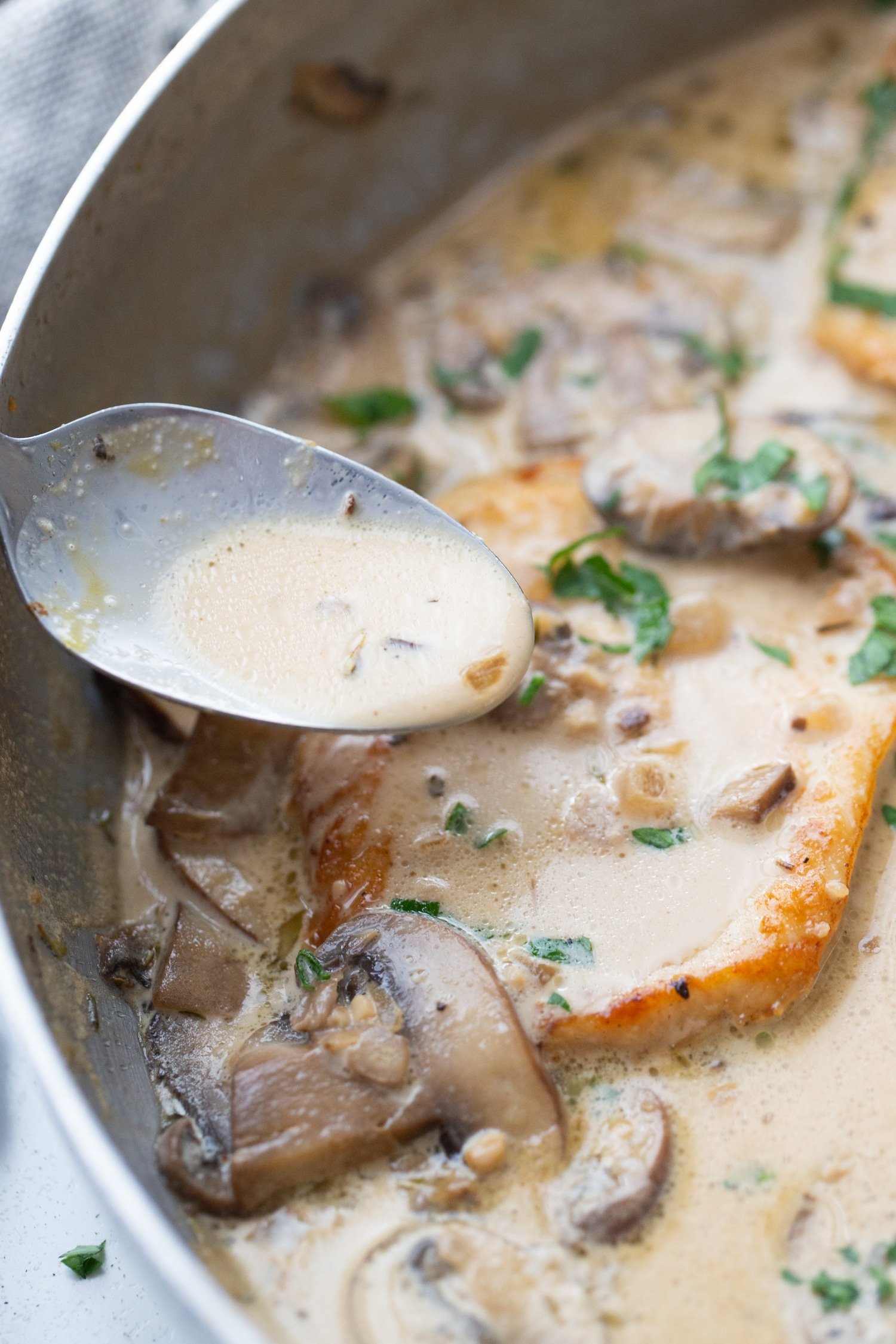 browned chicken in a skillet with marsala cream sauce and mushrooms