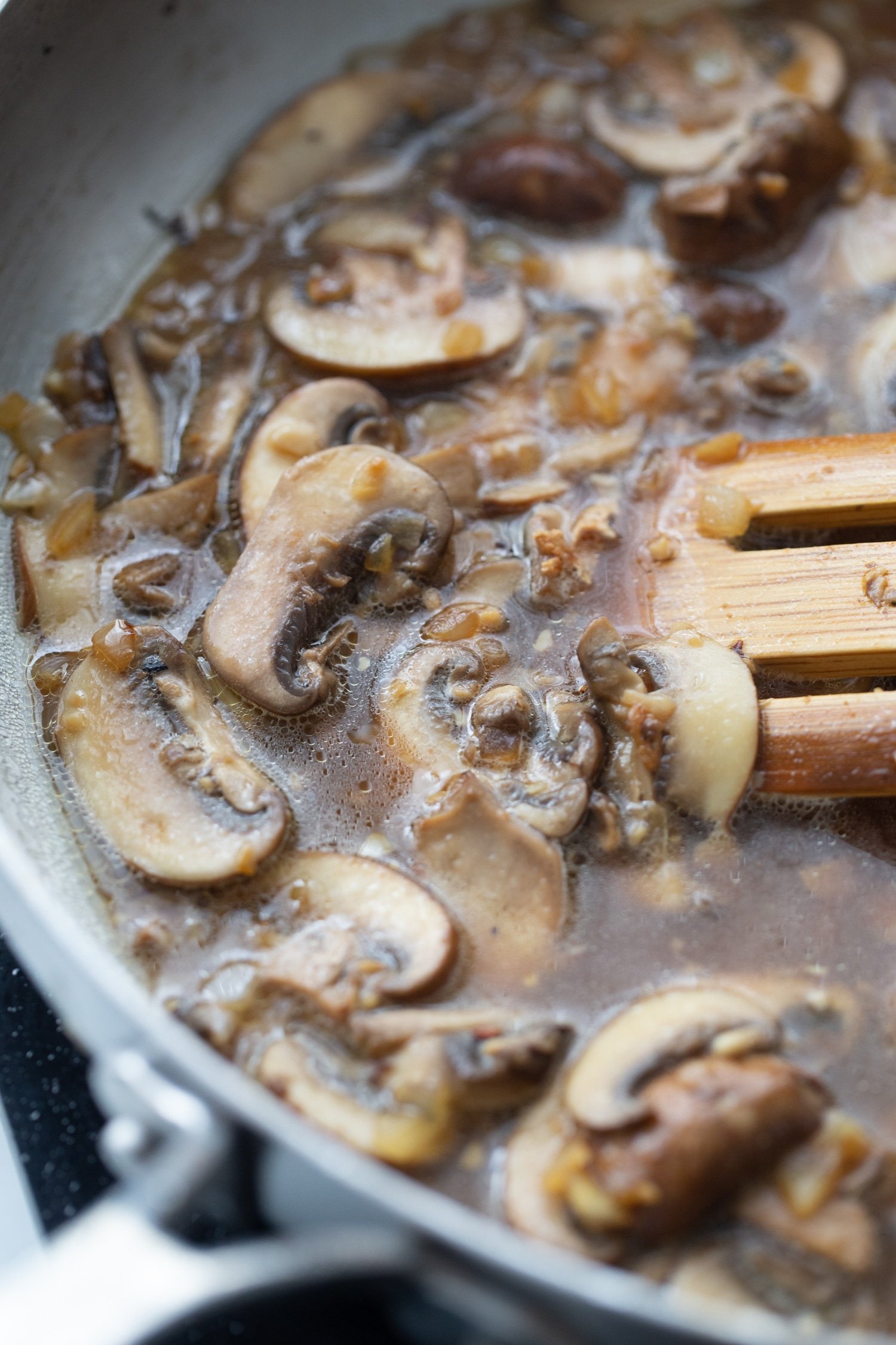 sliced mushrooms in a skillet with chicken stock