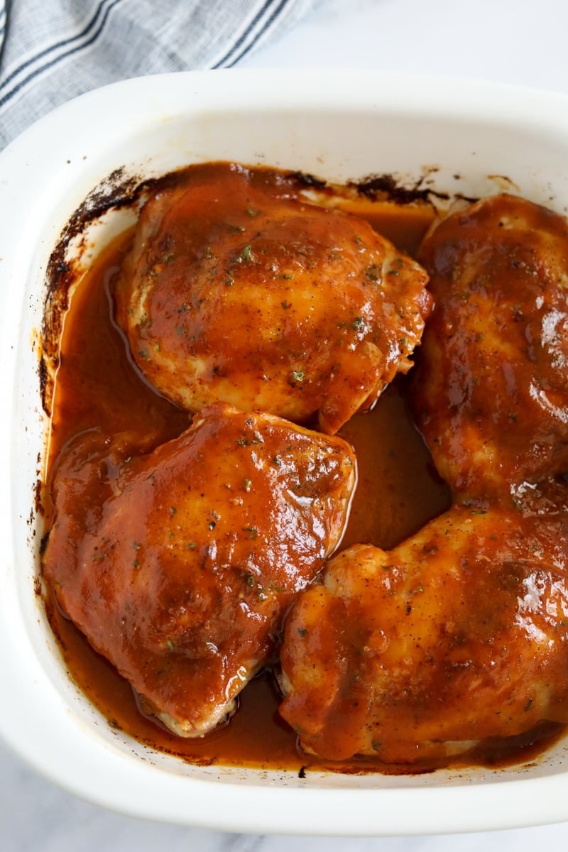 chicken thighs coated in BBQ sauce in a baking dish