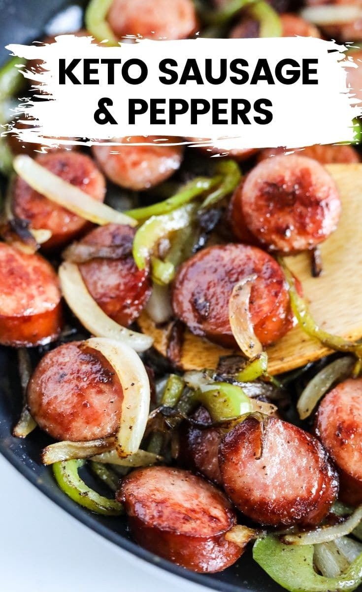 sausage with peppers and onions in a skillet with a wooden spoon.