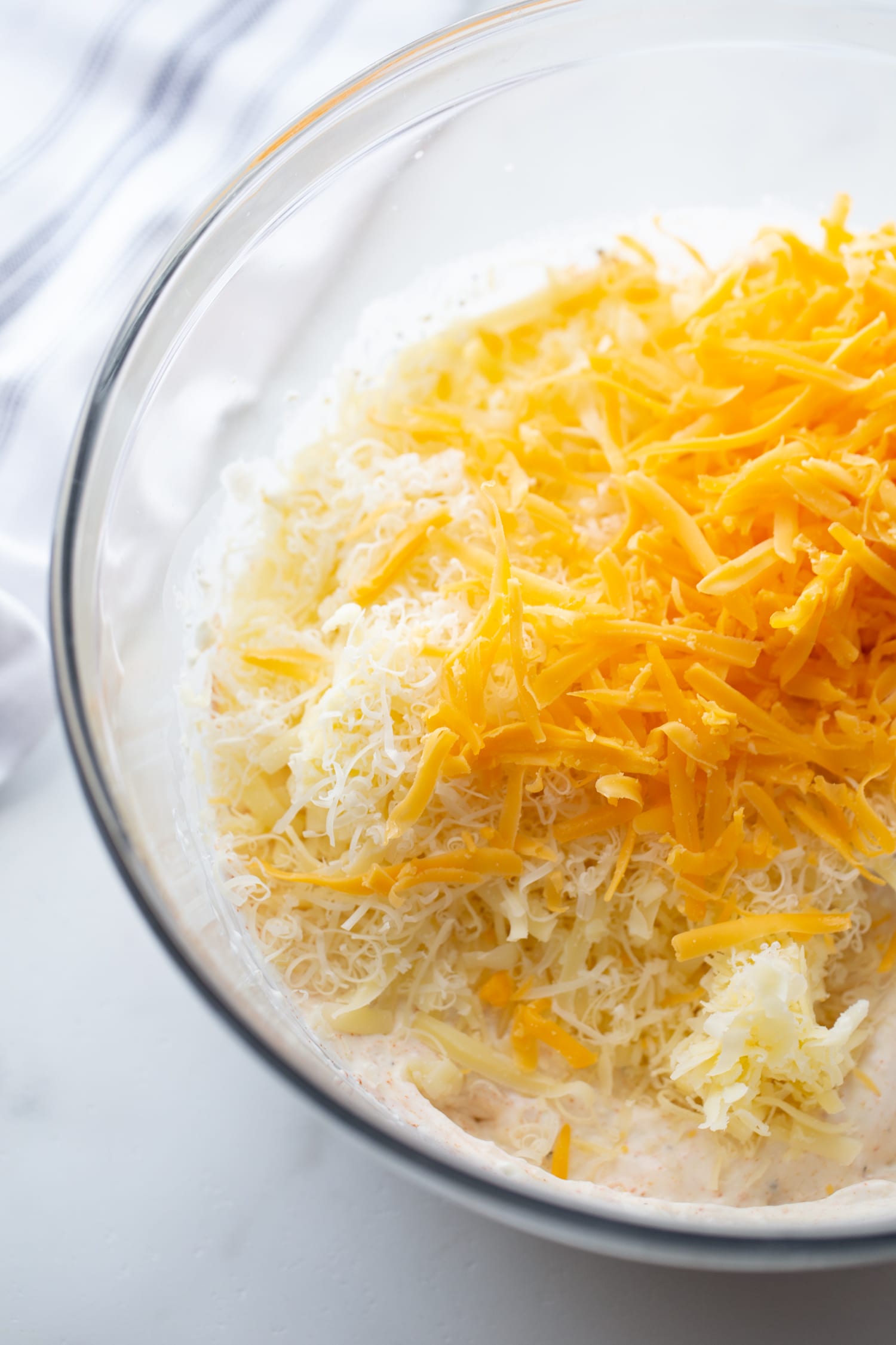 shredded cheddar, gruyere and parm cheeses in a bowl for casserole