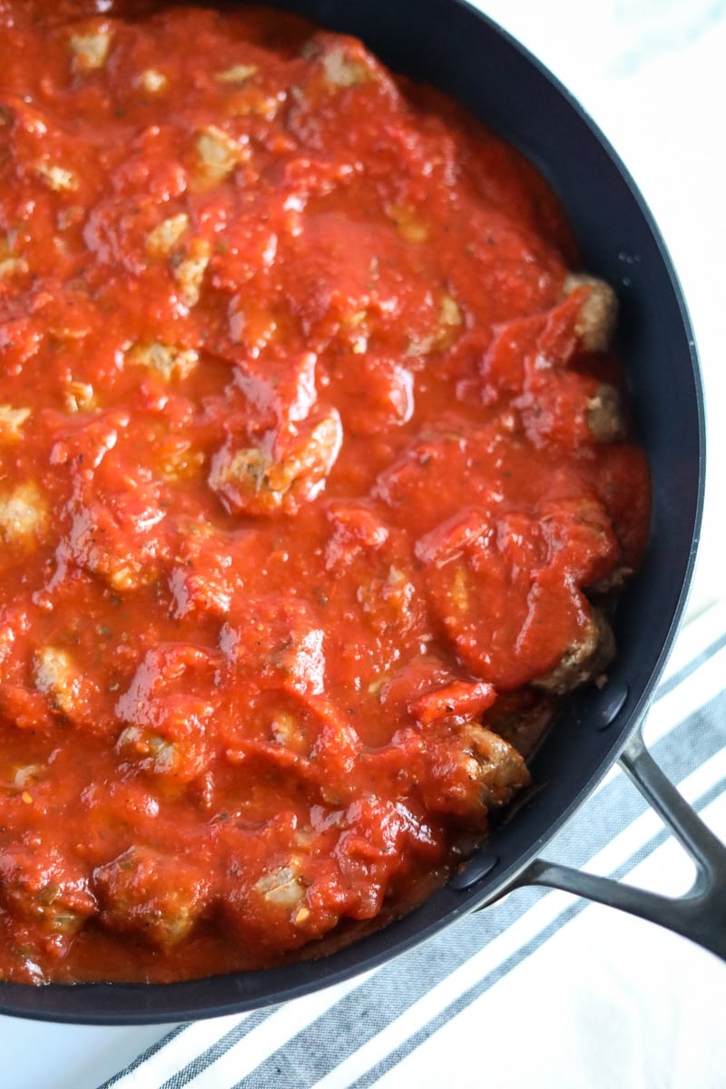 tomato sauce over sausages in a baking dish