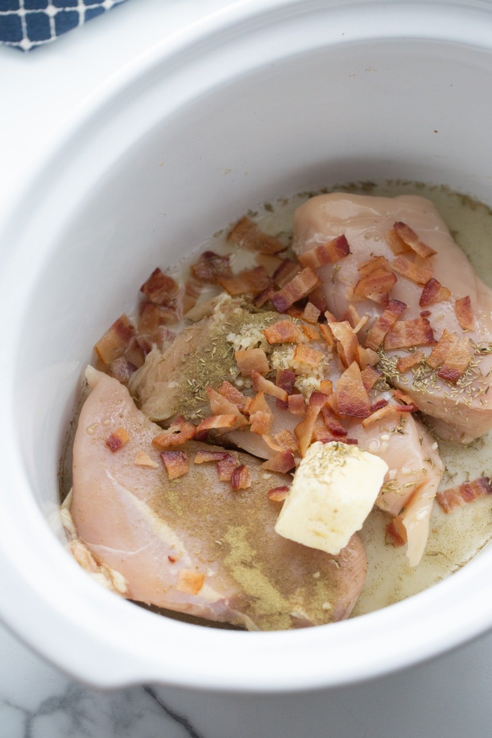 chicken with crumbled bacon, butter, seasonings, and broth in a crock pot