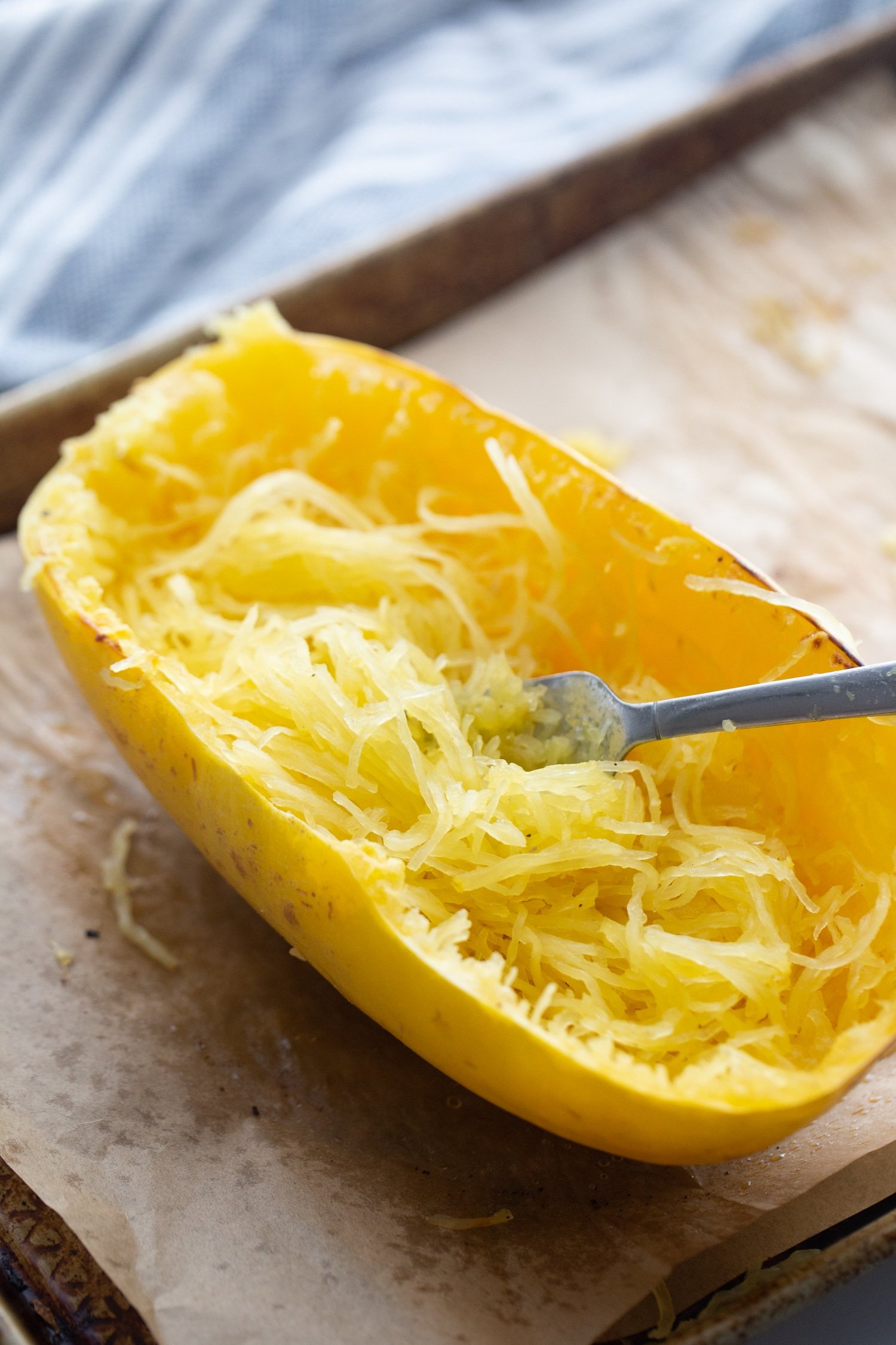 roasted spaghetti squash cut open with a fork in half of it. 