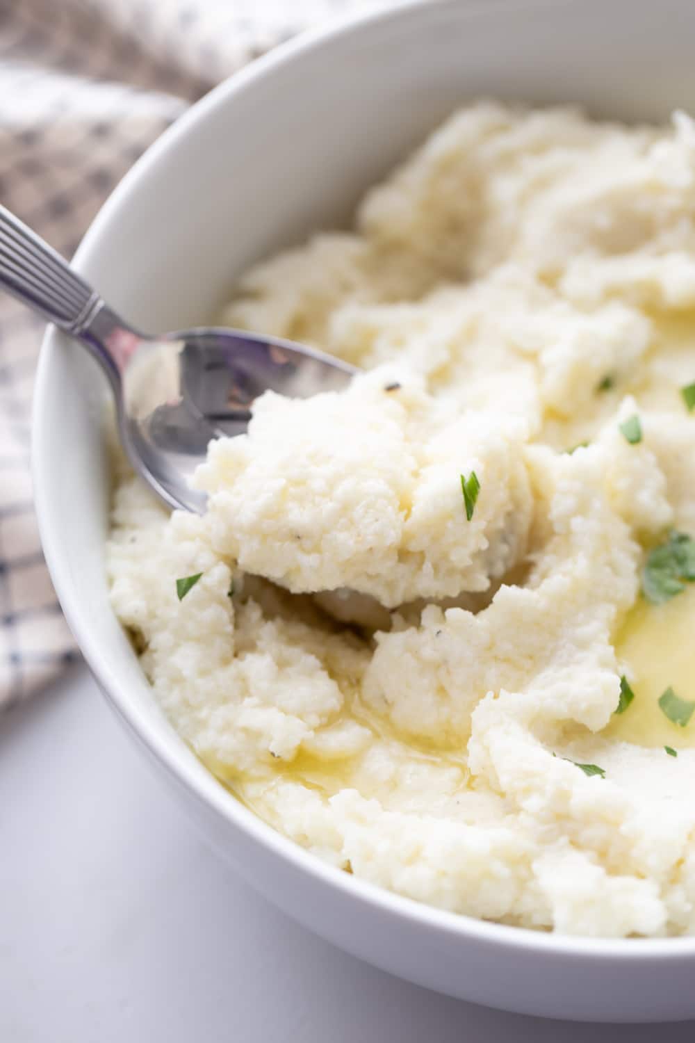 mashed cauliflower keto in a white bowl with spoon 