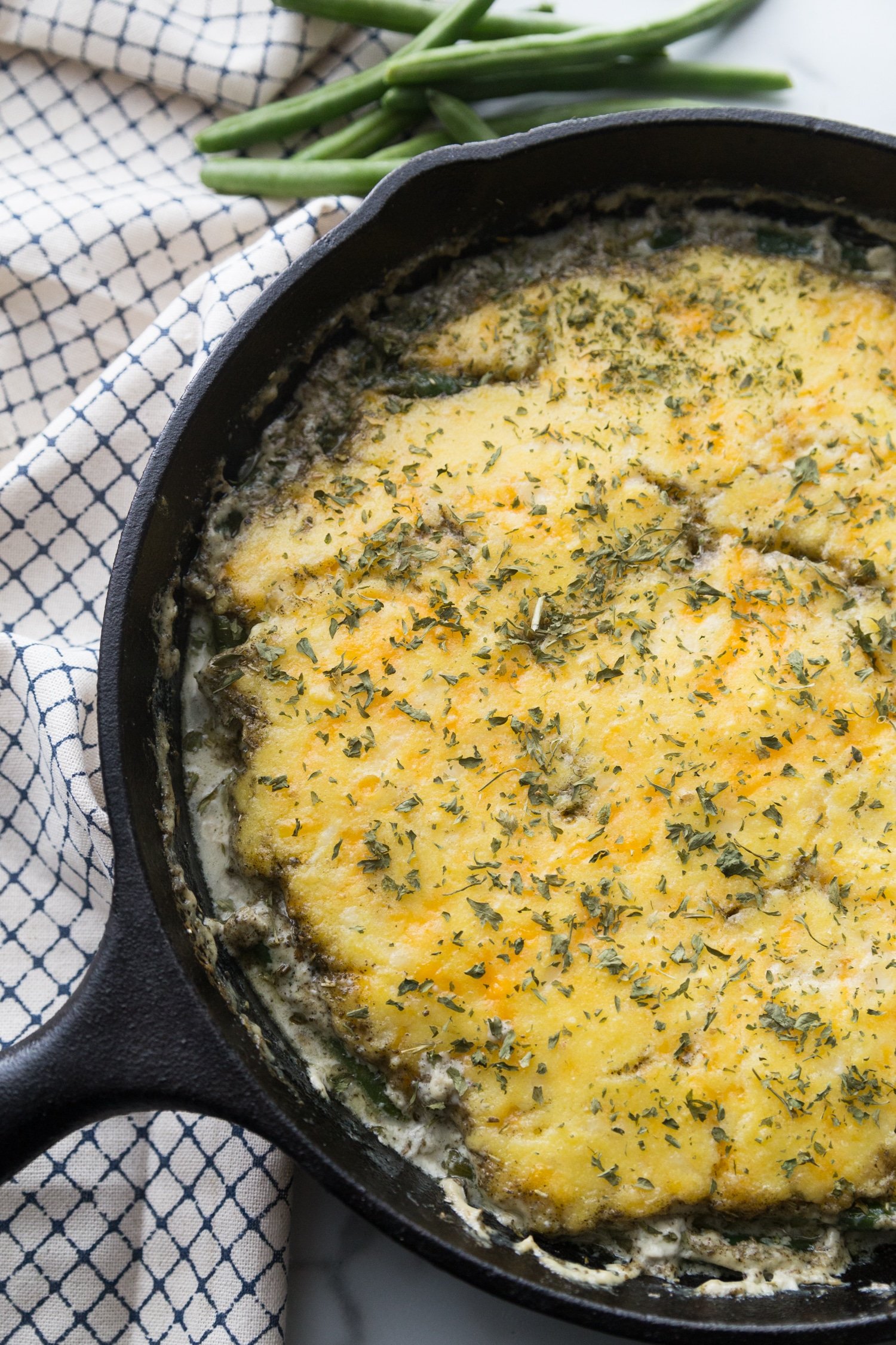 cast-iron skillet is filled with chicken pot pie with cheesy dough spread on top