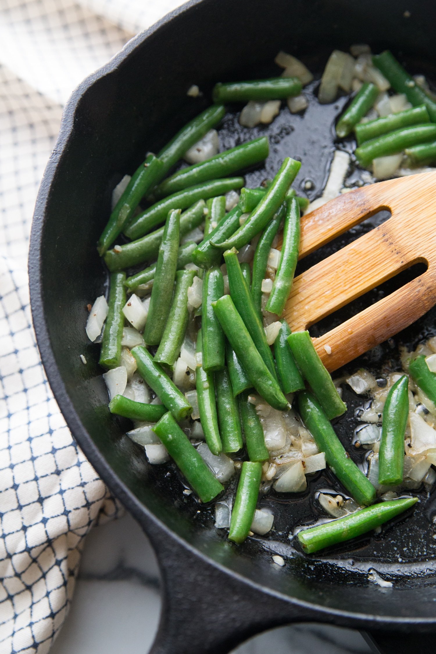 green beans are sauteeing in a pan with onions