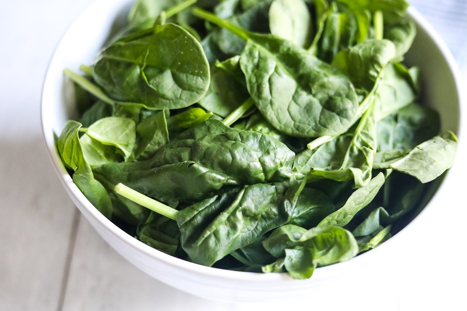 fresh spinach leaves in a white bowl