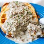 two chaffles on a blue plate covered in low-carb sausage gravy