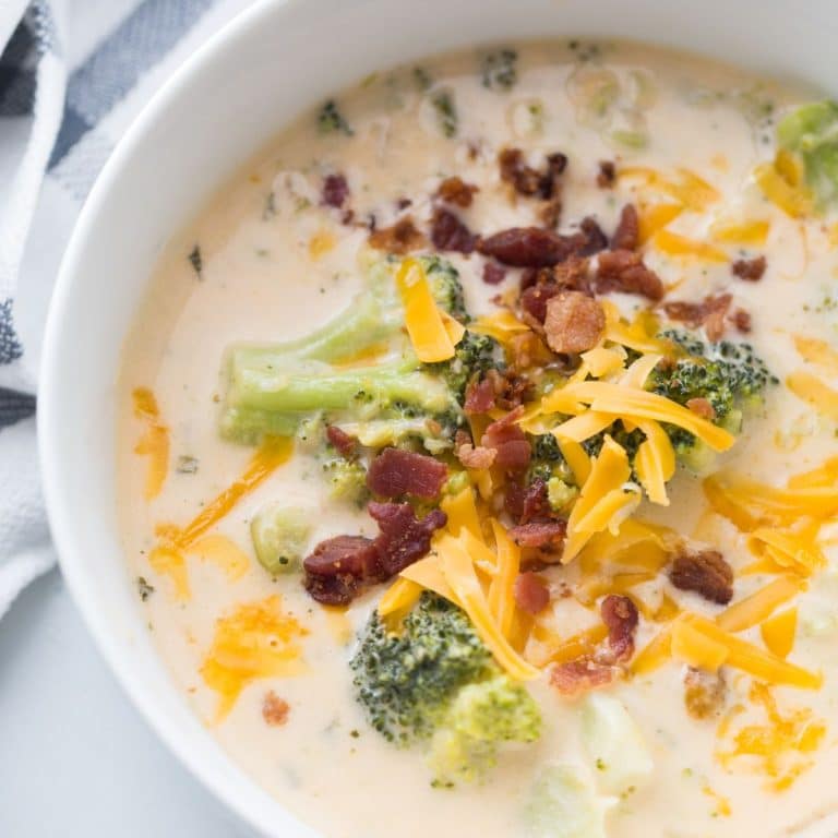 Close up of Instant Pot Broccoli Cheese Soup in a white bowl with cheese and bacon on top.