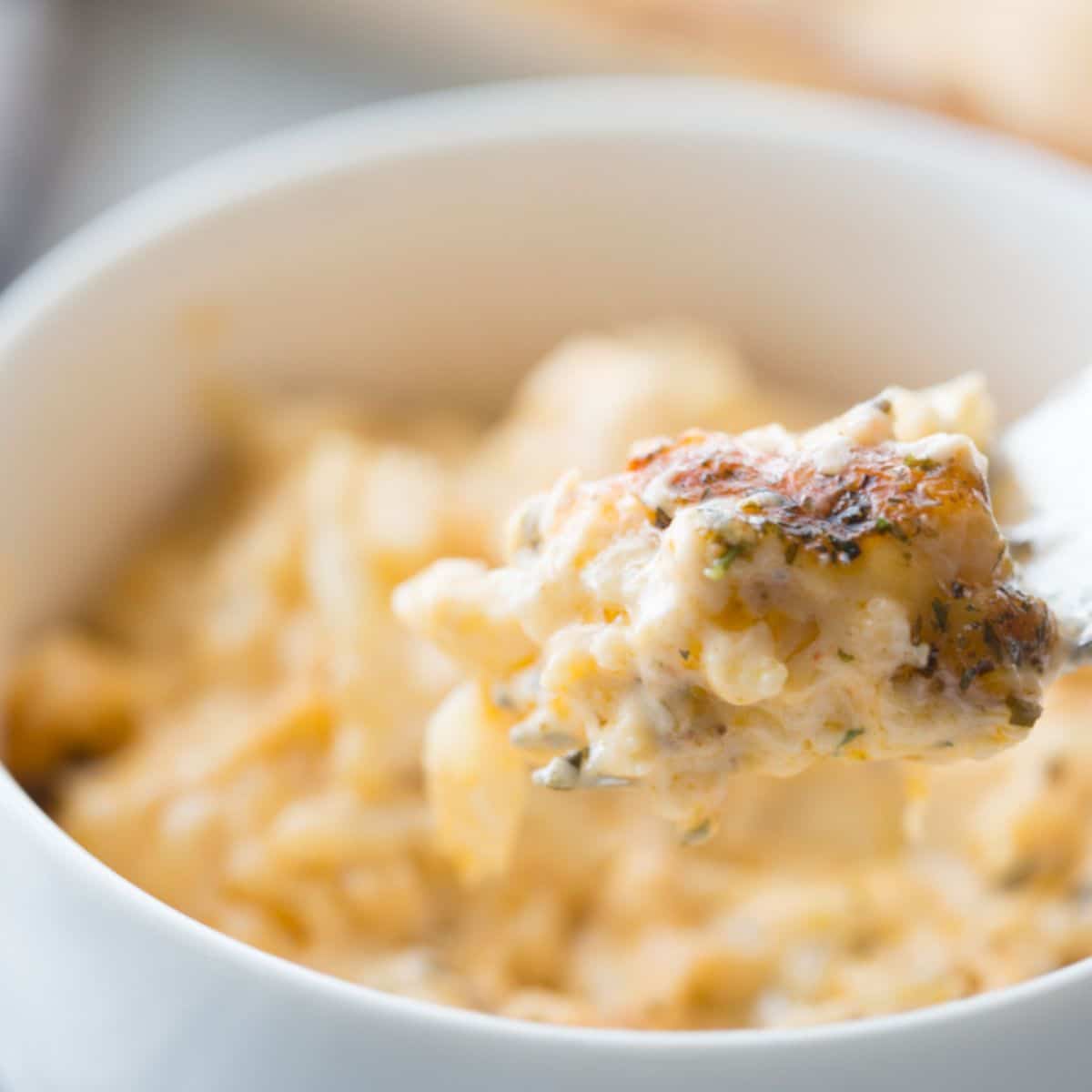 featured image of cauliflower Mac n cheese in a white bowl with a bite on a spoon