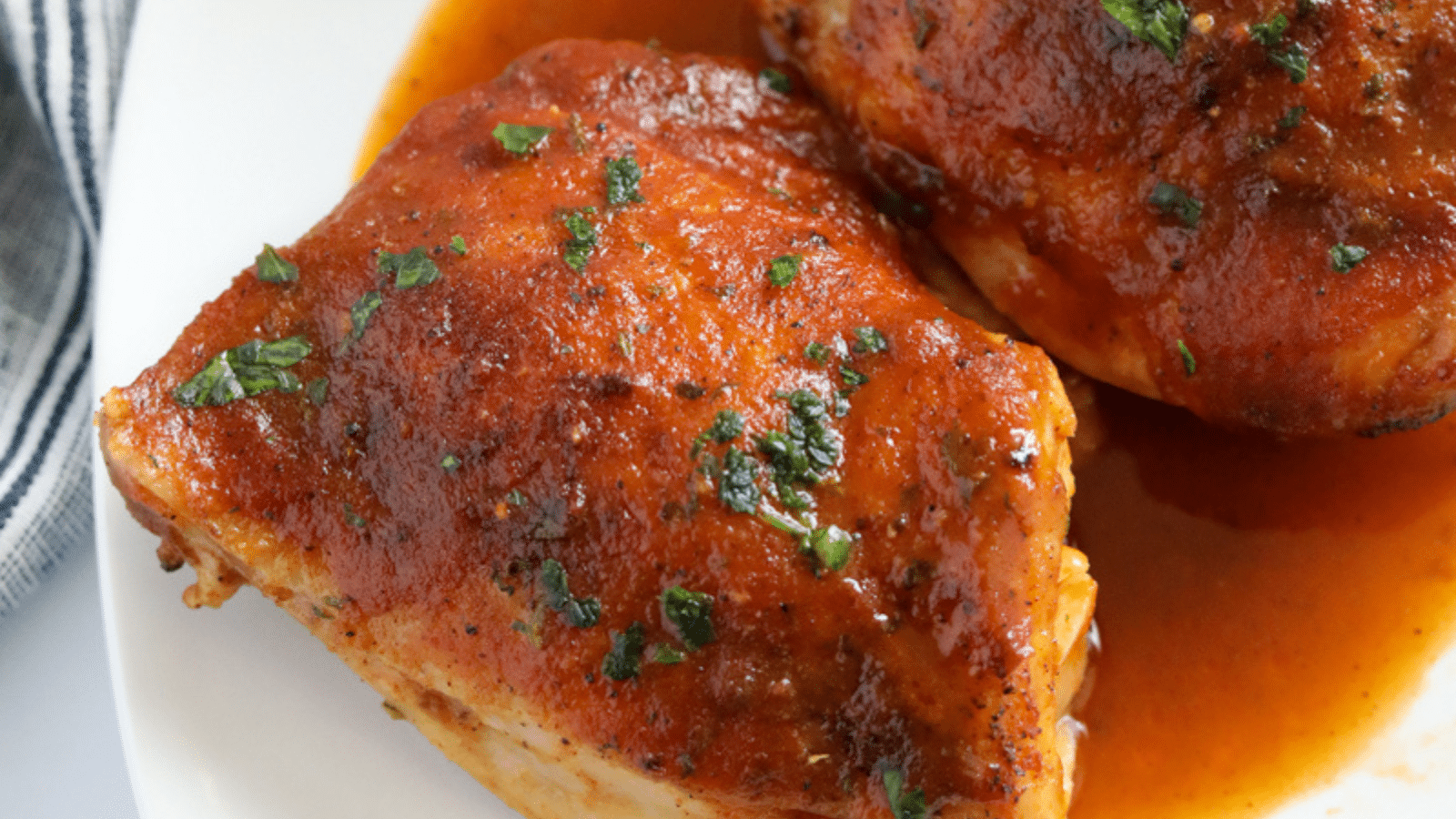 Close up of baked chicken thighs covered with bbq sauce 