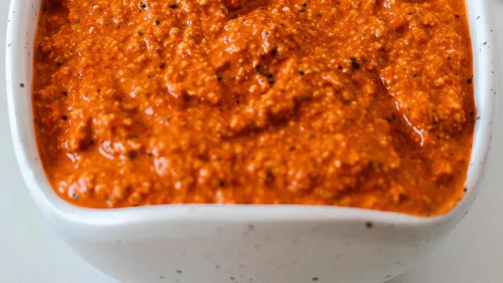 Close up of roasted red pepper pesto in white bowl