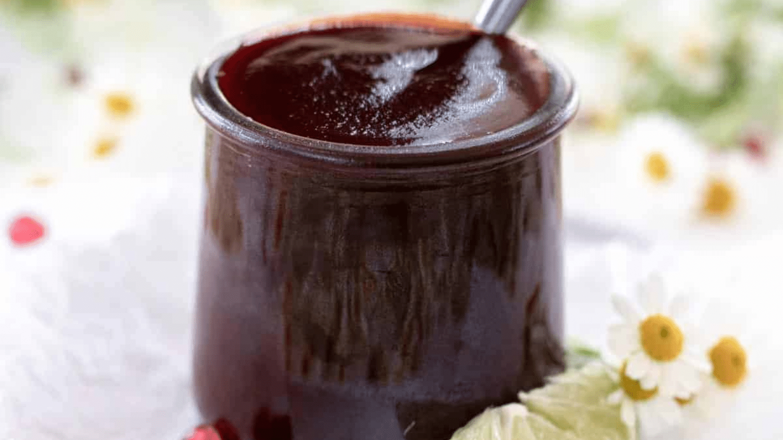 Pomegranate BBQ sauce in small jar with spoon in it