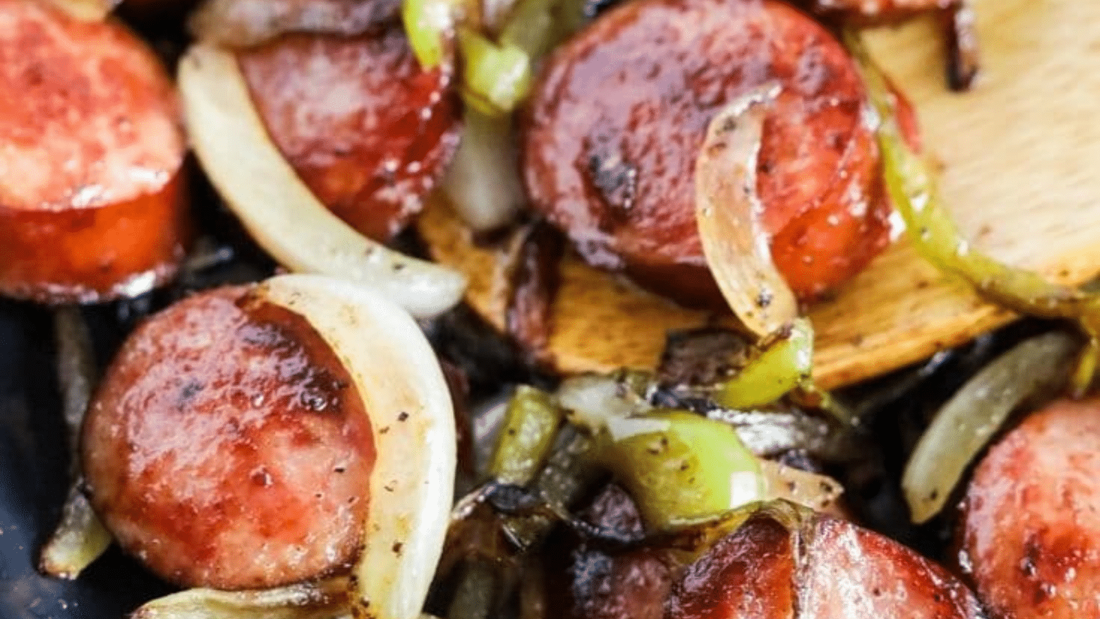 Close up of smoked sausage with peppers and onions in a skillet