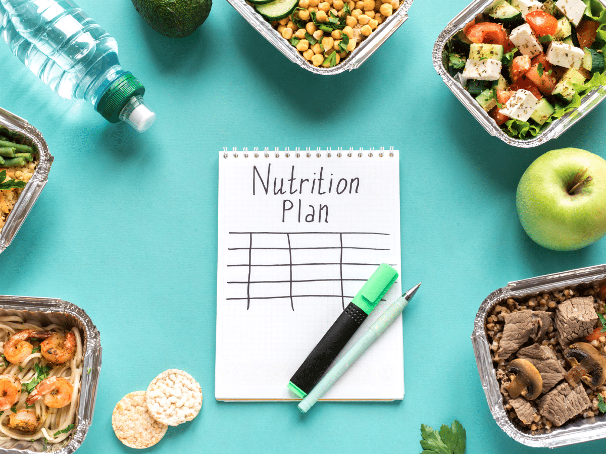 paper with words nutrition plan on teal table with low carb foods surrounding it