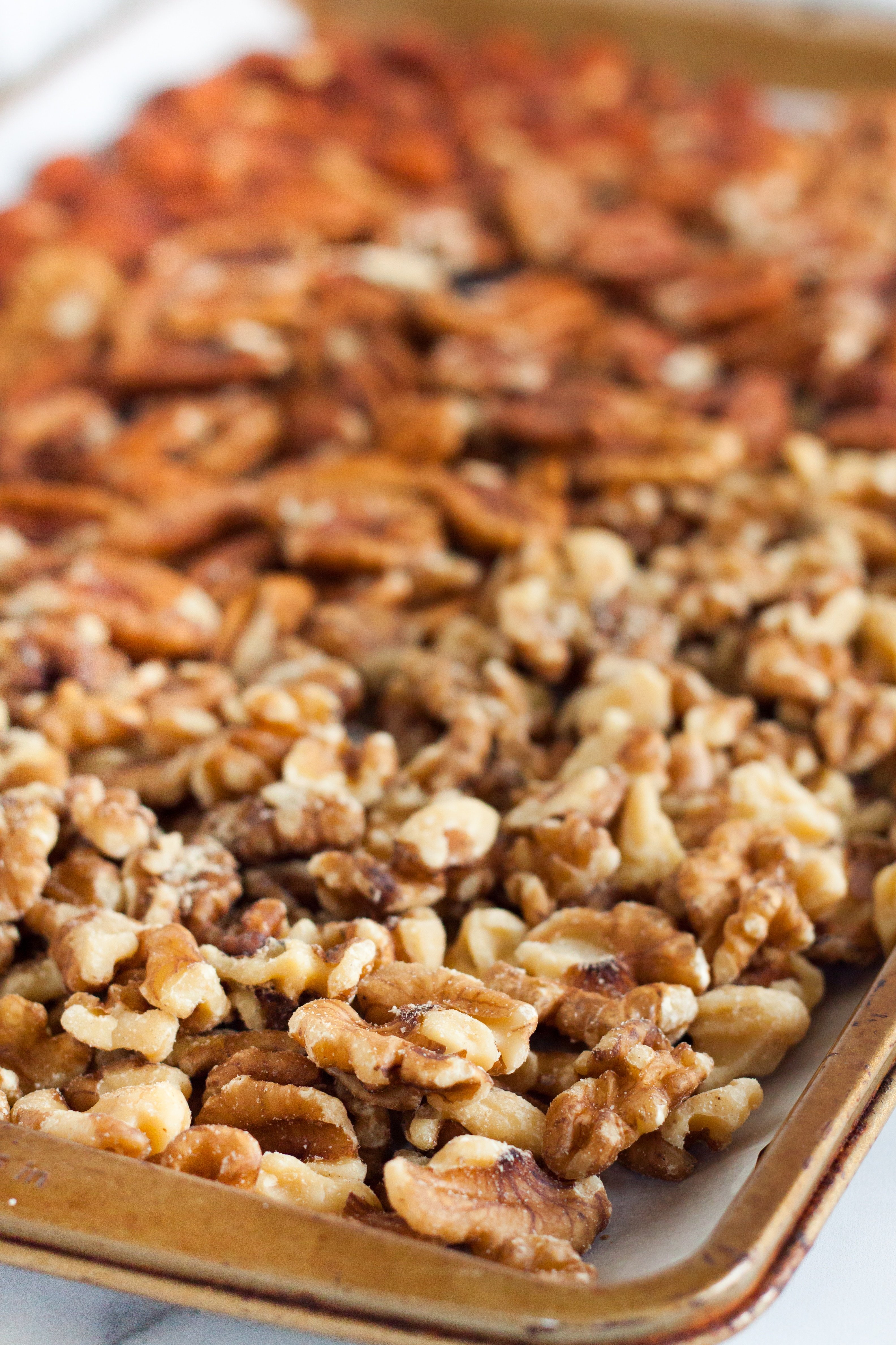 Baking sheet with Almonds, Walnuts, and Pecans placed evenly across with a drizzle of coconut oil.