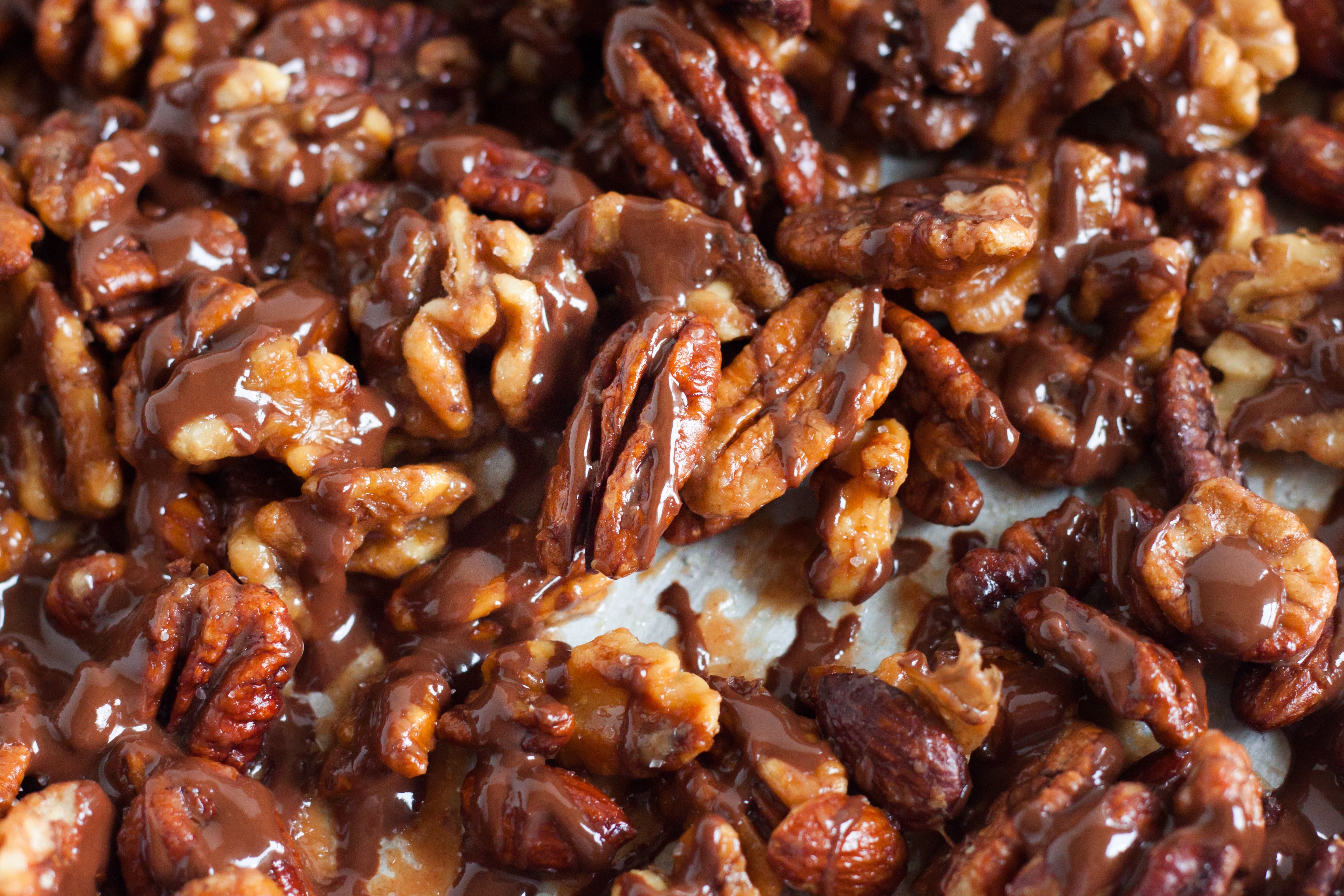 baking sheet with pecans, almonds, and walnuts drizzled with chocolate.