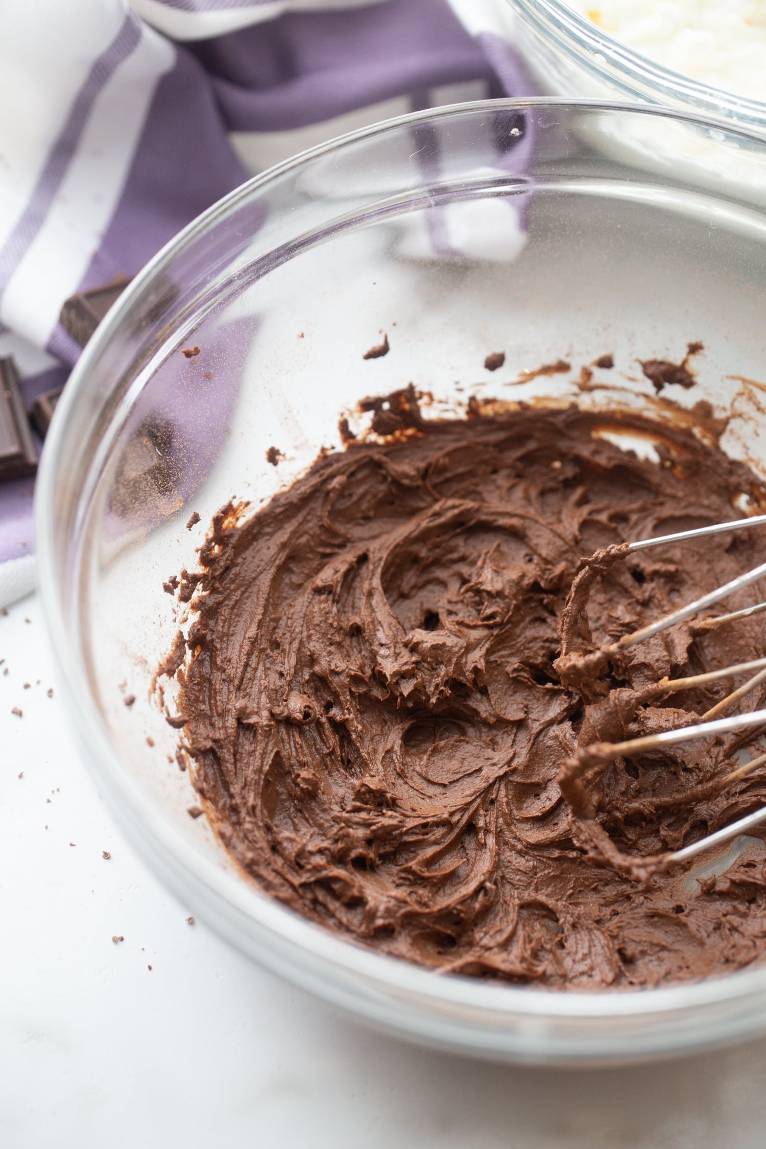 Image of chocolate mousse being mixed together with electric mixer in glass mixing bowl