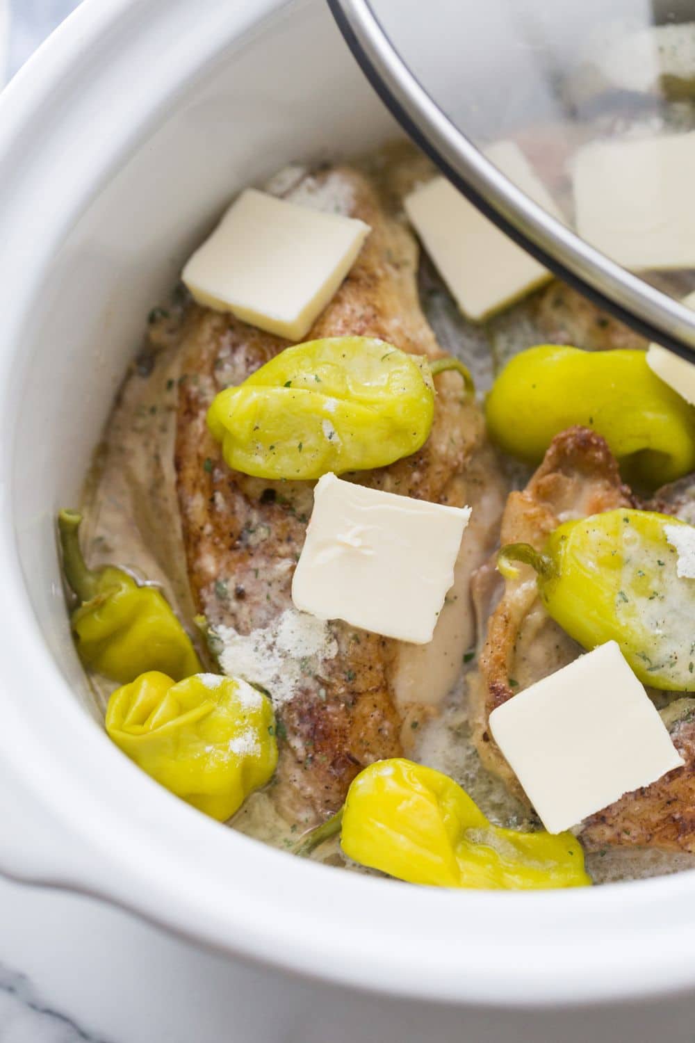 image of chicken breast, breast, and peppers placed in white slow cooker