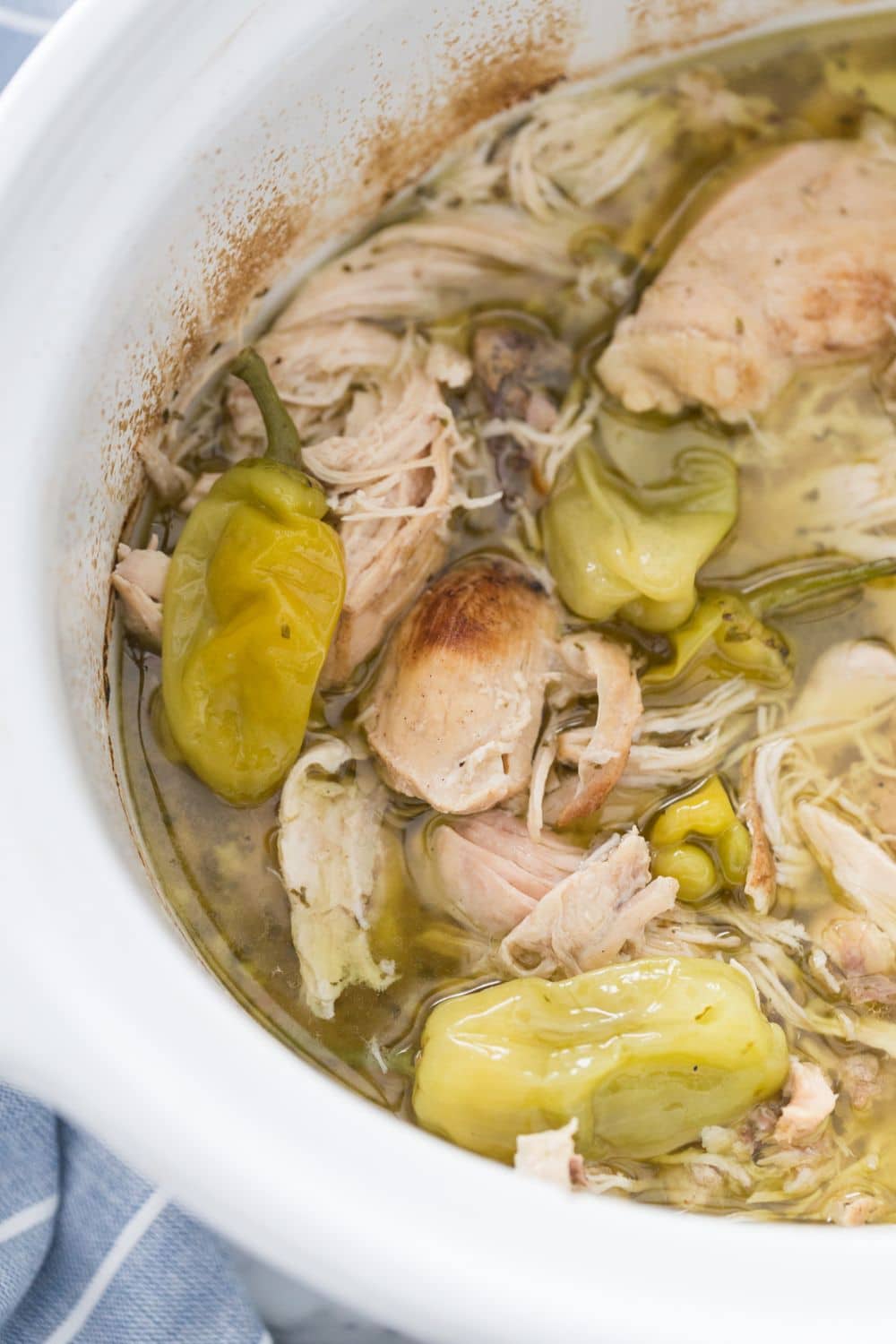 Image of cooked and shredded chicken with peppers in white slow cooker