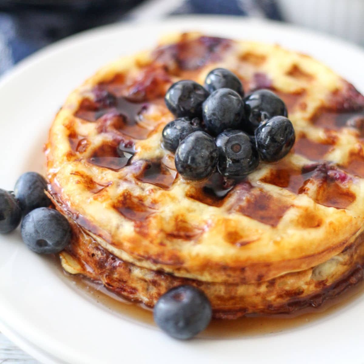 square image of blueberry chaffle topped with blueberries and sugar-free maple syrup