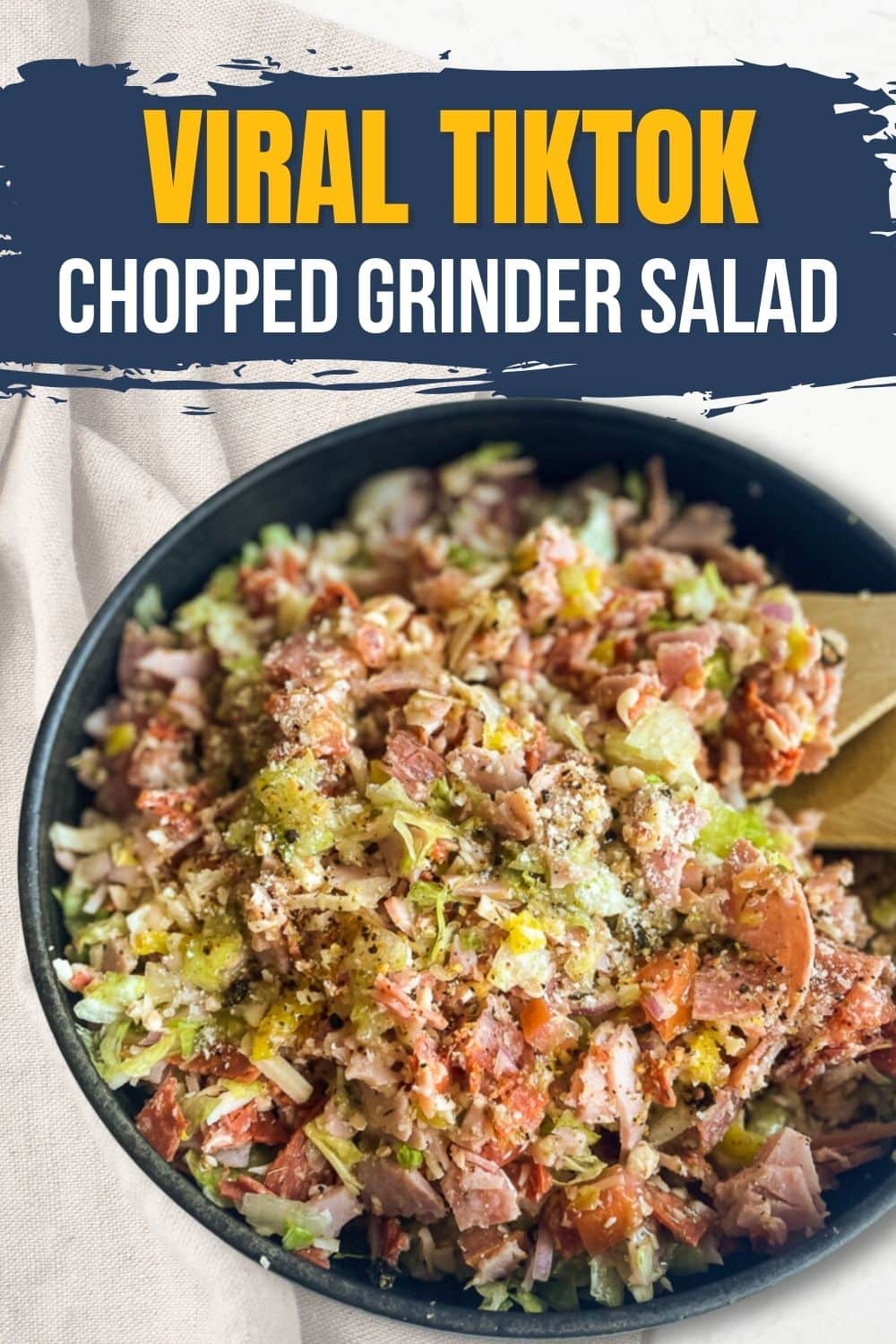  Viral TikTok Chopped Grinder Salad in a black bowl, showcasing a vibrant mix of chopped meats, cheeses, lettuce and vegetables, with a text overlay highlighting the dish's viral popularity on the social media platform.