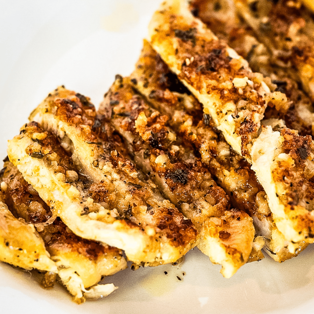 Square image featuring sliced, oven-baked Garlic Parmesan Chicken Cutlets, showcasing the tender and juicy texture of the perfectly cooked dish.