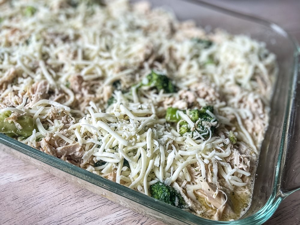 crock pot chicken with broccoli and Olive Garden Dressing in 9x13 casserole dish, topped with shredded cheese, ready for broiling