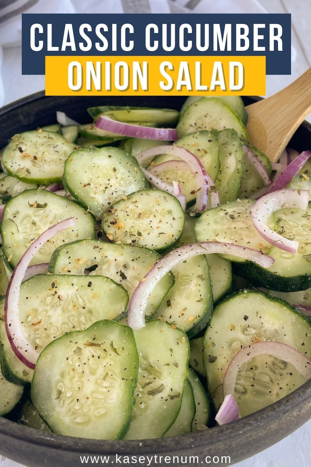 Close-up of keto cucumber onion salad in a black bowl with a wooden spoon, featuring fresh cucumbers, red onions, and a tangy vinegar dressing.