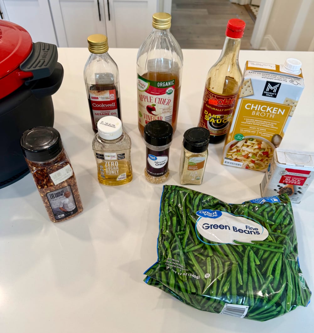 Ingredients laid out for Keto Slow Cooker Honey Garlic Chicken and Green Beans, including chicken tenders, frozen green beans, soy sauce, sesame oil, apple cider vinegar, low-carb honey substitute, garlic, and spices.
