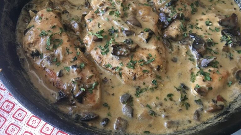 creamy keto chicken in mushroom sauce in a skillet, garnished with fresh herbs