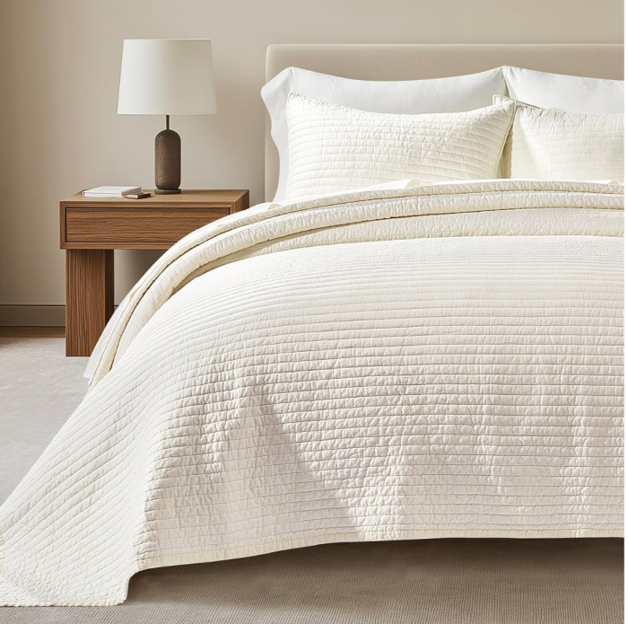 Cotton Sateen Channel stock image on quilt on a bed with a night stand and lamp